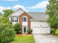 Charming two-story home featuring a brick facade, two-car garage, and well-manicured lawn under a blue sky at 12529 Old Timber Rd, Charlotte, NC 28269