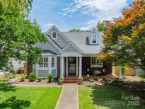 Charming gray and brick home with manicured lawn and inviting front porch with rocking chairs at 2021 Charlotte Dr, Charlotte, NC 28203