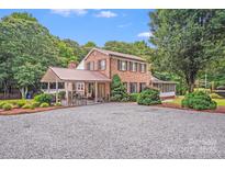 Charming two-story brick home featuring an attached covered patio and a spacious gravel driveway at 211 Drive Inn Rd, Locust, NC 28097