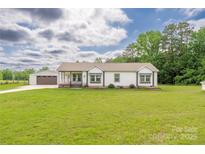 Charming single-story home with a covered porch, green lawn, and detached garage, providing ample space and curb appeal at 326 Teeter Rd, Mooresville, NC 28115