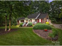 Charming brick home featuring a welcoming front porch, lush landscaping, and mature trees at 635 Timberlane Trl, Salisbury, NC 28147