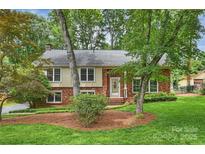 Charming brick home with lush front yard and mature trees, offering a serene and inviting curb appeal at 7050 Knightswood Dr, Charlotte, NC 28226