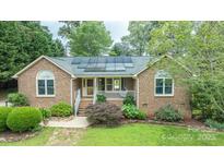 Charming brick home featuring solar panels, a cozy front porch, and beautifully landscaped front yard at 8259 Camelia Ln, Denver, NC 28037
