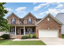 Charming two-story brick home featuring a welcoming front porch, attached two-car garage, and well-maintained landscaping at 10198 Tintinhull Dr, Fort Mill, SC 29707
