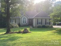 Charming single-story home featuring a well-manicured lawn and flower garden, framed by mature trees, creating a serene setting at 1369 Timberlane Ter, Mooresville, NC 28115