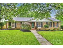 Charming brick home featuring a beautifully landscaped front yard with lush green grass and mature trees at 1961 Runnymede Ln, Charlotte, NC 28211