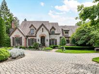 Stunning stone house with a circular driveway and manicured landscaping for enhanced curb appeal at 2240 La Maison Dr, Charlotte, NC 28226