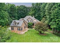 Beautiful brick and stone home with lush green lawn and mature trees offers exceptional curb appeal at 2314 Winding Oaks Trl, Waxhaw, NC 28173
