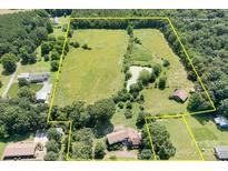 Expansive aerial view of a large estate with a pond, lush greenery, and multiple structures surrounded by trees at 24008 Carriker Rd, Albemarle, NC 28001