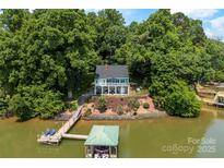 Beautiful waterfront home featuring a private dock and boat house surrounded by lush trees at 812 Bell Post Rd, Belmont, NC 28012
