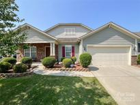 Charming single-story home featuring a manicured lawn and a two-car garage with brick and vinyl siding at 1228 Tranquil Falls Ln, Matthews, NC 28104