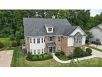 Beautiful two-story home showcasing a lush, landscaped front yard and a harmonious mix of brick and stone accents at 16229 Loch Raven Rd, Huntersville, NC 28078