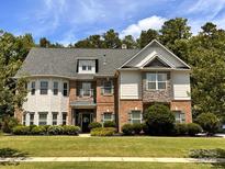 Inviting brick and stone two-story home with manicured lawn and blooming flowerbeds at 16229 Loch Raven Rd, Huntersville, NC 28078