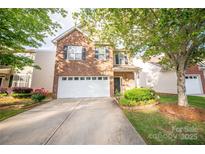 Charming two-story brick home featuring a white garage door, landscaped yard, and mature trees at 16525 Kettlewell Ln, Charlotte, NC 28277
