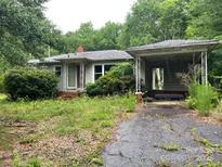 Shows the front exterior of a one-story home with an attached carport and overgrown front yard at 1769 S Nc 16 Hwy, Denver, NC 28037