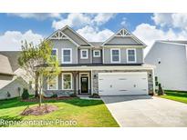 Charming two-story home with gray siding, stone accents, a well-kept lawn, and an attached two-car garage at 2227 Caravan Ln # 43, Denver, NC 28164
