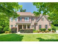 Charming two-story brick home with manicured lawn, mature trees, and a covered front porch at 2785 Disney Pl, Indian Land, SC 29707