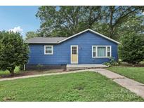 Charming blue single-story home with a yellow door, set against a backdrop of mature trees at 407 Cherry St, Belmont, NC 28012