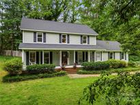 Charming two-story home with a welcoming front porch, black shutters and lush landscaped front yard at 4848 Spicewood Dr, Charlotte, NC 28227