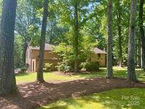 Brick home surrounded by lush trees, offering privacy and a serene natural setting at 5109 Goldcrest Dr, Indian Trail, NC 28079