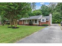 Charming single-story home featuring a brick facade, well-manicured lawn, and a long driveway at 1344 Shannonhouse Dr, Charlotte, NC 28215