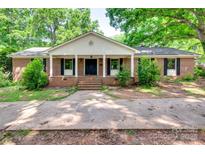 Charming brick home features a quaint front porch, mature trees, and lush landscaping at 257 Amity Dr, York, SC 29745