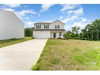 Charming two-story home with a two-car garage and a long driveway, nestled on a partially wooded lot at 3077 Light Ridge Sw Ct, Concord, NC 28027