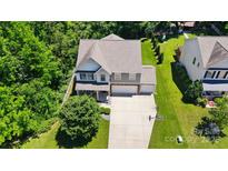 Two-story home boasts a spacious driveway, lush lawn, and mature trees for a serene setting at 3106 Crosswind Dr, Fort Mill, SC 29707