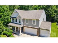Attractive two-story home featuring gray siding, stone accents, attached garages, and a charming front porch at 3106 Crosswind Dr, Fort Mill, SC 29707