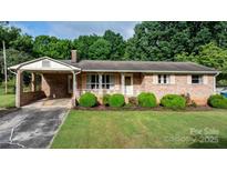 Charming brick home with manicured lawn and decorative white railing on the front porch at 518 W School St, Maiden, NC 28650