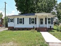 Charming single-story home with white siding, black shutters and well-maintained lawn and a walkway at 6225 Macon St, Charlotte, NC 28208