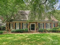 Charming brick home with a well-manicured lawn, black shutters, and lush landscaping at 828 Colville Rd, Charlotte, NC 28207