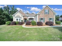 Charming single-Gathering home featuring a stone facade, manicured lawn, and beautiful landscaping at 909 Autumn Glen Ct, Lake Wylie, SC 29710