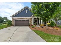 Charming home features a blue facade, stone accents, a brown garage door, and a well-maintained front yard at 1712 Askern Ct, Waxhaw, NC 28173