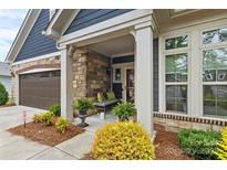 Inviting front porch featuring stone accents, neutral bench, and lush landscaping at 1712 Askern Ct, Waxhaw, NC 28173
