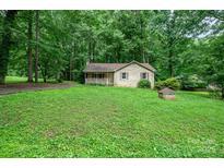 Charming single-story home with a brick exterior and a cozy front porch surrounded by lush trees and greenery at 1802 Deer St, Charlotte, NC 28214