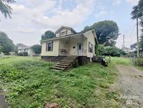 Quaint two-story home with a covered front porch and tidy landscaping at 205 Woods St, Mount Holly, NC 28120