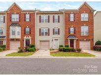 Charming townhome with brick and siding exterior, red shutters, well-kept lawn, and driveway with attached garage at 2169 Belle Vernon Ave, Charlotte, NC 28210