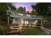 Charming two-story home features a stone facade, a screened porch, and a spacious deck, nestled among mature trees at 4043 Windward Dr, Fort Mill, SC 29708