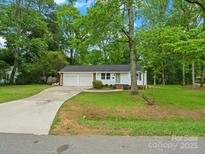 Charming single-story home featuring a two-car garage and a lush, green lawn with mature trees at 4126 Howie Cir, Charlotte, NC 28205