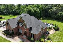 Stately two-story brick home with a well-manicured lawn, lush greenery, and an inviting pool in the backyard at 4359 Whitetail Ln, Midland, NC 28107