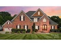 Charming brick home with manicured lawn, decorative shutters, and inviting front entrance at dusk at 4359 Whitetail Ln, Midland, NC 28107