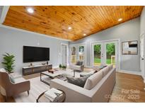 Bright living room features a vaulted wood ceiling, neutral walls, and double doors leading to the outdoors at 4838 Keats Ave, Charlotte, NC 28212