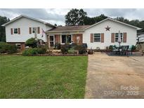 Charming home with a lush lawn, beautiful landscaping, and inviting outdoor seating area at 1895 Sandy Cir, Newton, NC 28658