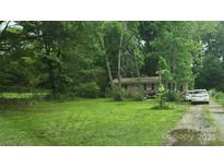 Modest brick home with a lush green lawn, framed by mature trees and shrubs at 3715 Patricia Nw Dr, Concord, NC 28027