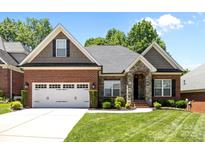 Charming brick home with a two-car garage, stone accents, manicured lawn and plentiful bushes and small shrubs at 4004 Saint Andrews Ct, Cramerton, NC 28032
