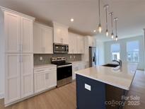 Modern kitchen features white cabinets, stainless steel appliances, and a stylish island with pendant lighting at 6013 Countess Dr # 51, Charlotte, NC 28217