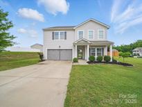 Charming two-story home featuring a well-manicured lawn, two-car garage, and inviting front porch at 6017 Fazio Ct, Harrisburg, NC 28075