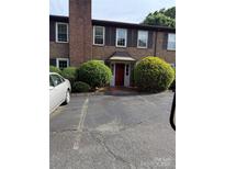 Traditional brick condo with a red door, decorative shutters, and mature landscaping at 921 Nottingham Dr # 6, Gastonia, NC 28054