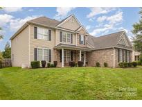 Charming two-story home with a well-maintained lawn, stone accents, and black shutters under a bright sky at 9814 Tompkins Ln, Waxhaw, NC 28173